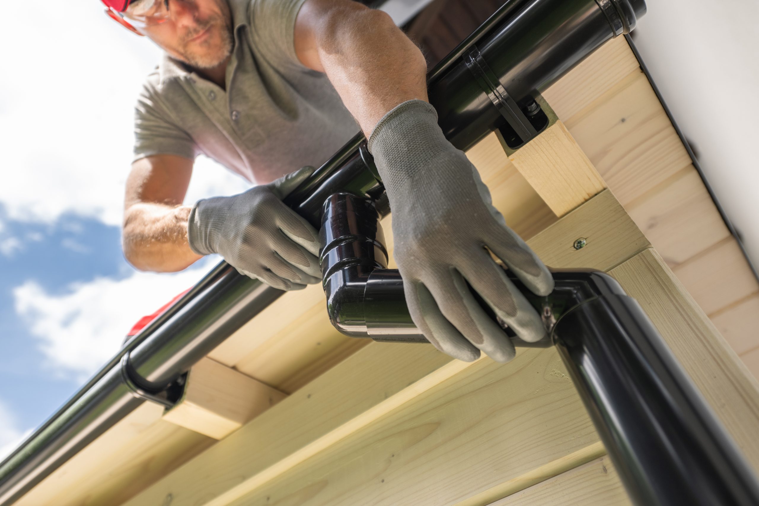 Roofer installing new gutter downpipe on property