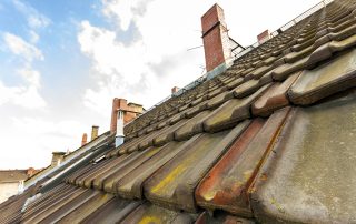 Old roof with roofing tiles and chimneys in london